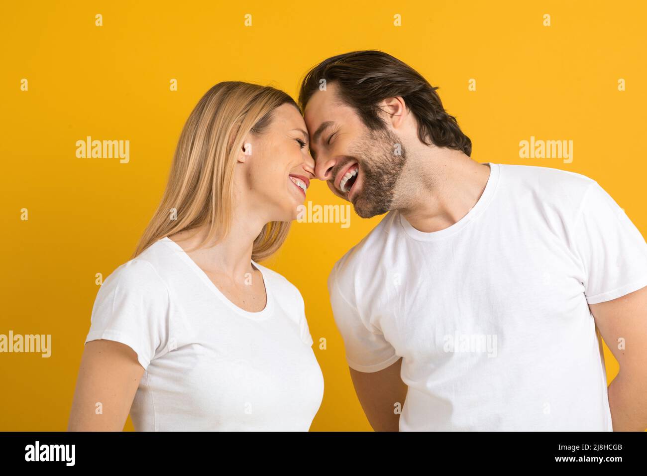 Fröhliche, fröhliche junge europäische Männer und Frauen in weißen T-Shirts haben Spaß und genießen einen zarten Moment Stockfoto