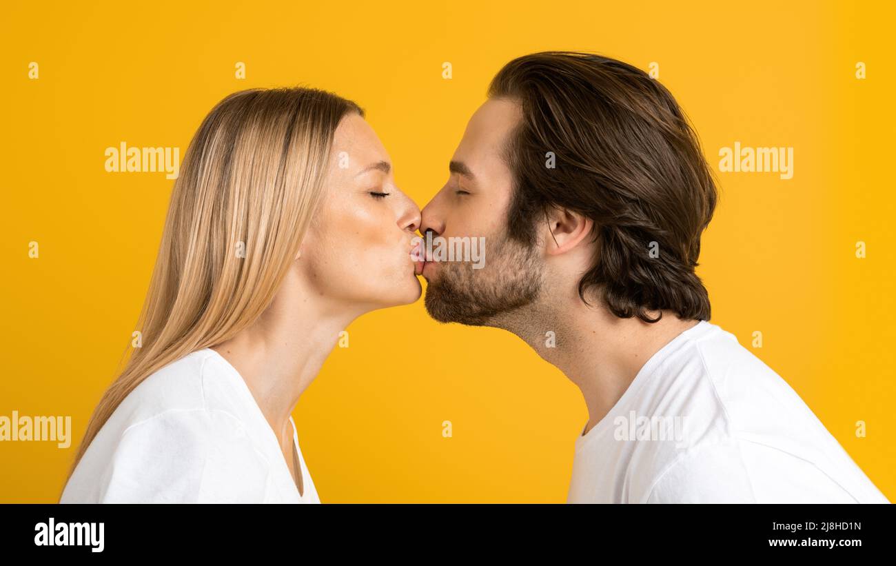 Frohes, tausendjähriges europäisches Mädchen in weißen T-Shirts küssen sich und genießen einen zarten Moment zusammen Stockfoto