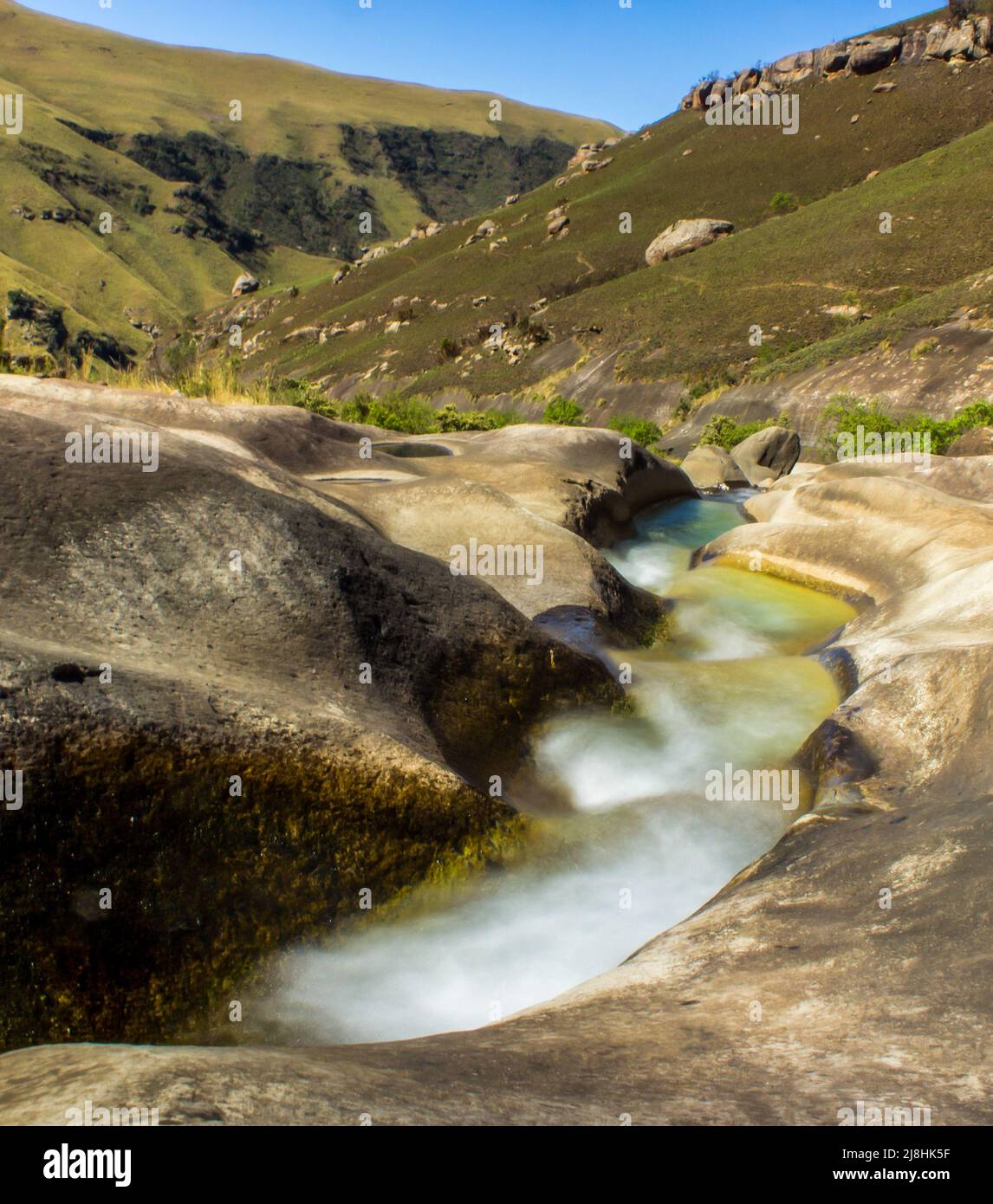 Langzeitbelichtung eines schnell fließenden Gebirgsstroms in den Drakensberg-Bergen Südafrikas an einem klaren, sonnigen Tag Stockfoto