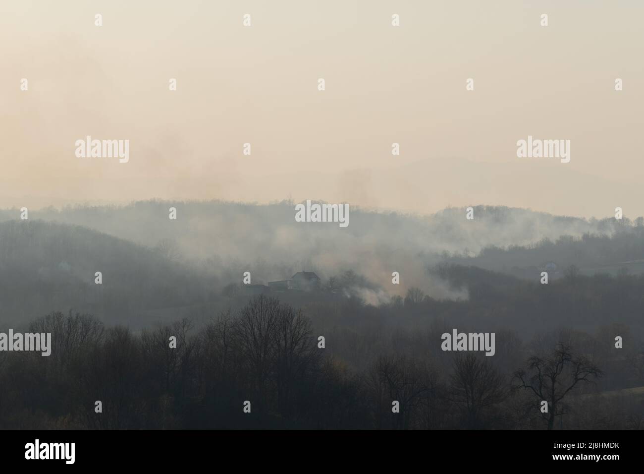 Waldbrand auf dem Land, Haus in Gefahr und rauchiger Himmel Stockfoto