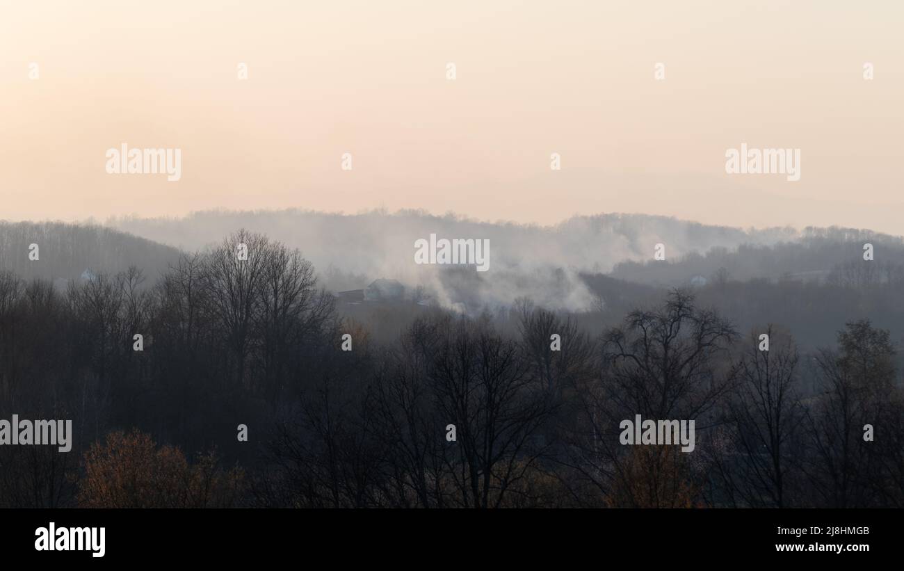 Waldbrand auf dem Land, Haus in Gefahr und rauchiger Himmel Stockfoto