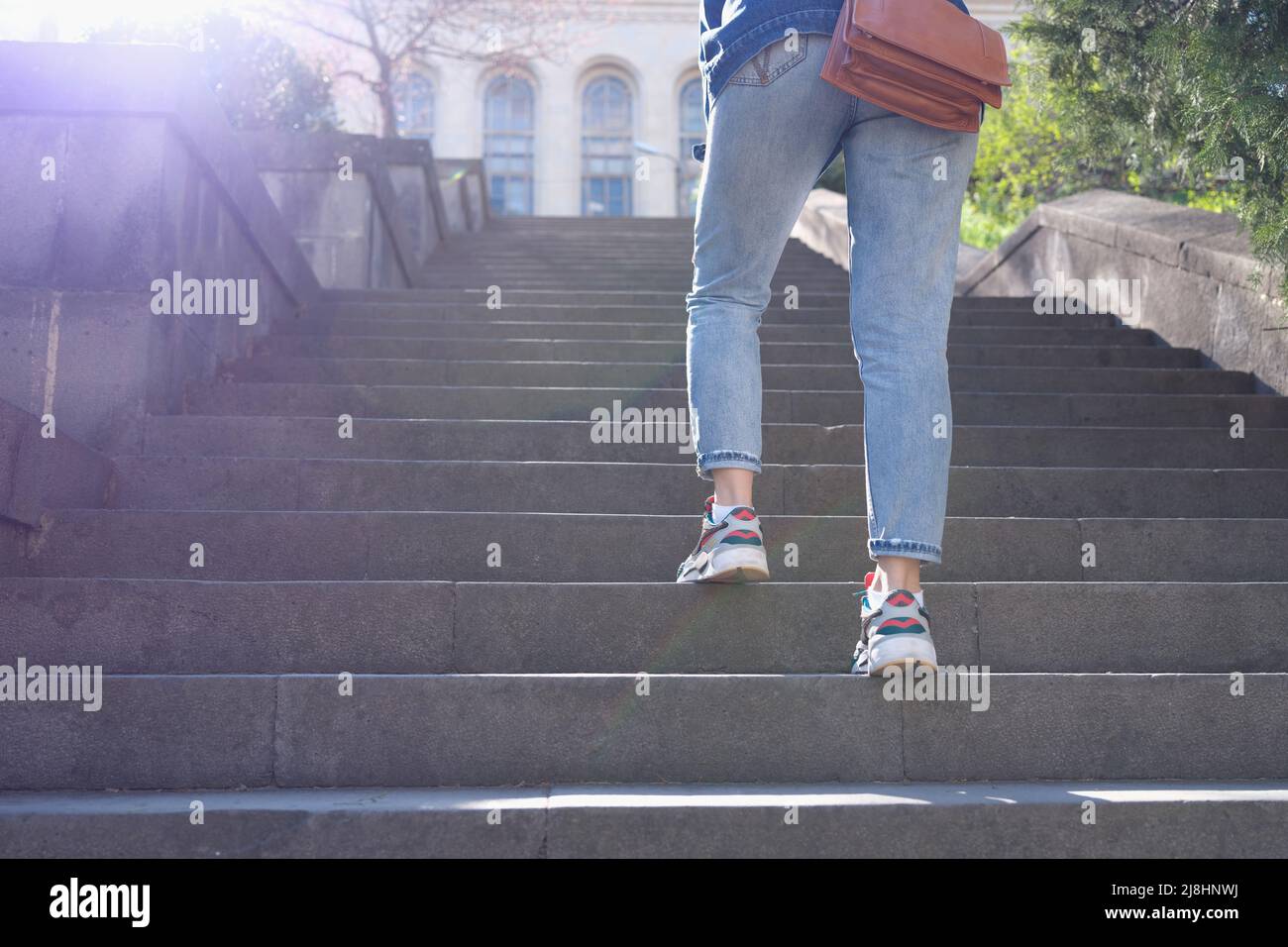 Frau in Jeans, die eine steile Treppe hinaufsteigt Stockfoto