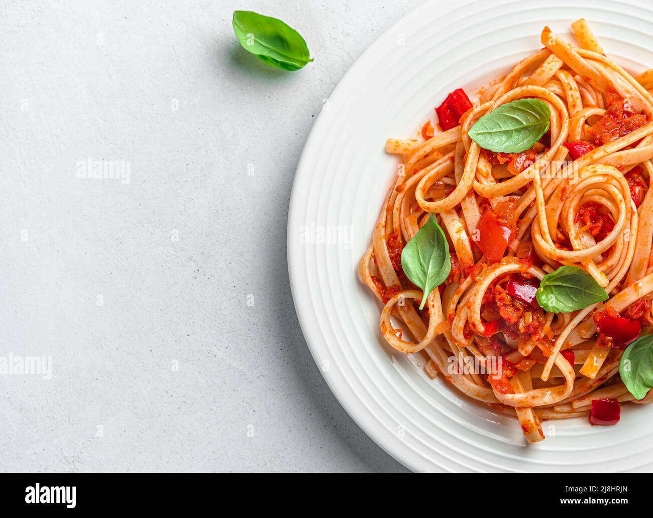 Linguini Pasta mit Tomatensauce und Basilikum auf grauem Hintergrund. Stockfoto