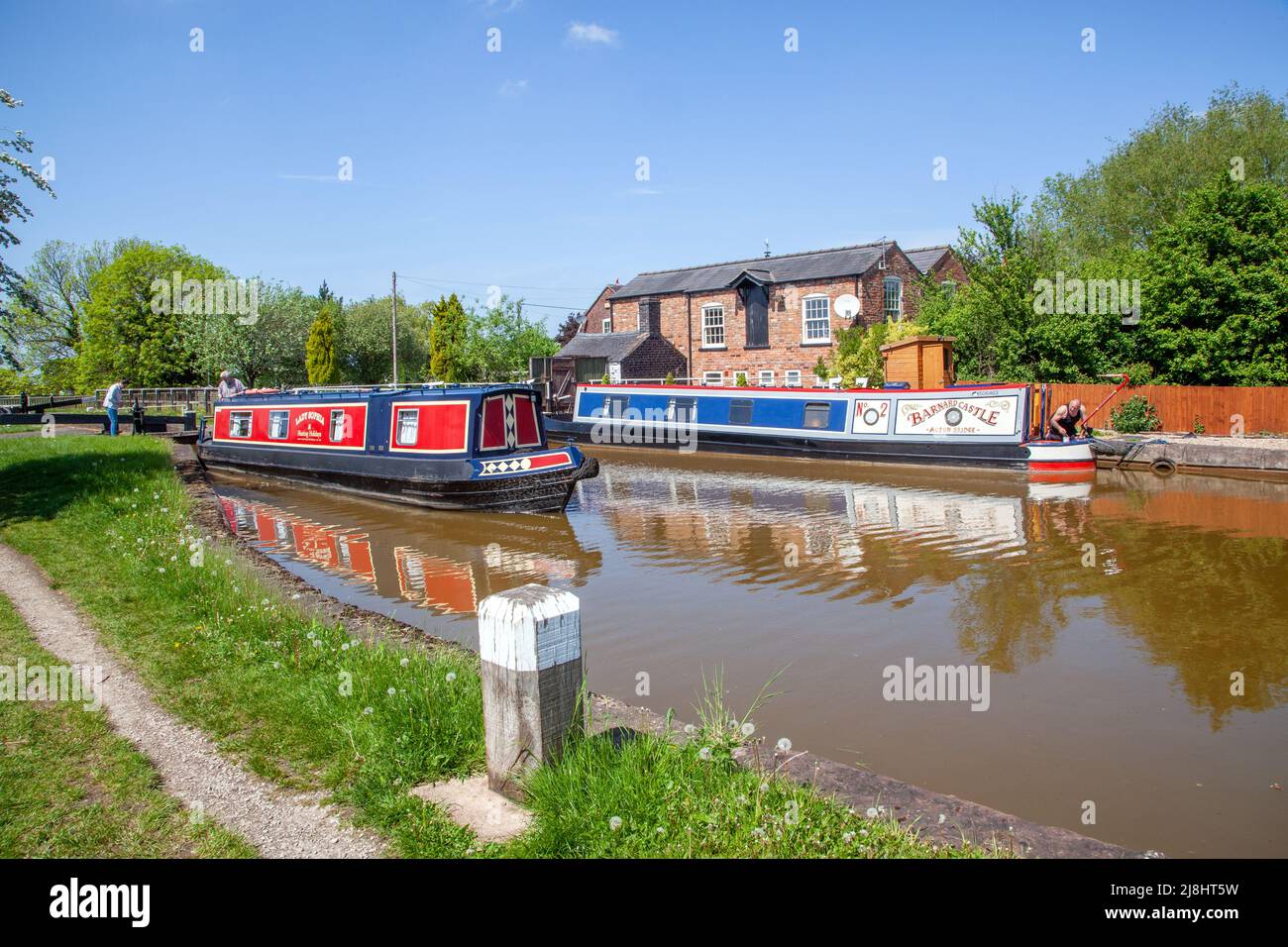 Mann und Frau auf einem gemieteten Kanalrundbooturlaub, der durch die Schleuse Nr. 57 auf dem Trent- und Mersey-Kanal bei Hassall Green in der Grafschaft Heshire England führt Stockfoto