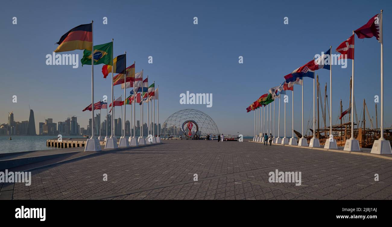 Die offizielle Countdown-Uhr der FIFA World Cup Qatar 2022 am malerischen Küstenfischerspot von Doha mit Flaggen der teilnehmenden Länder Stockfoto