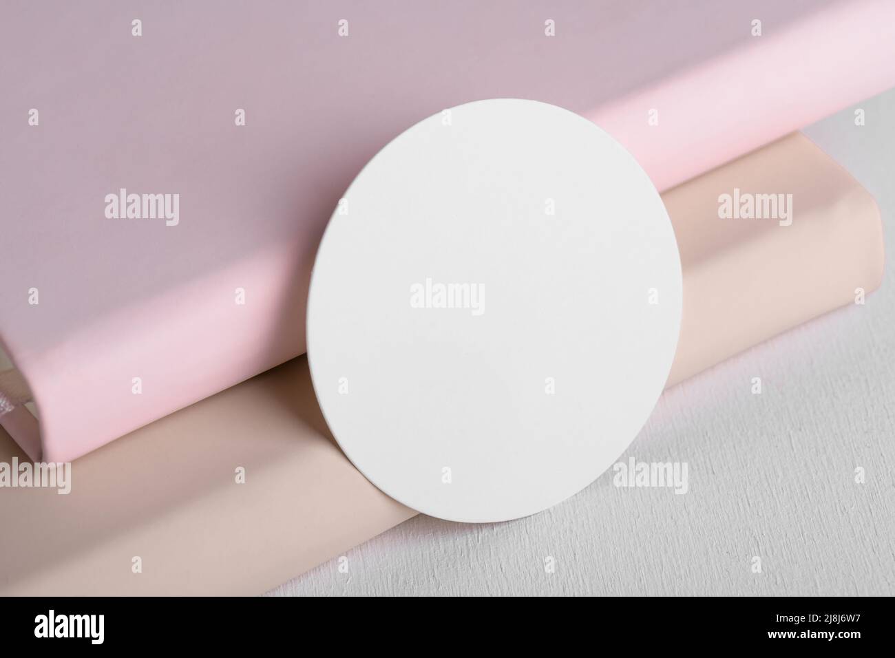Rundes weißes Geschenkanhänger-Modell auf beigem und rosa Buchhintergrund. Blankopapier kreisförmigen Preis Aufkleber Tag mockup, Sale und Black Friday Konzept, Element f Stockfoto