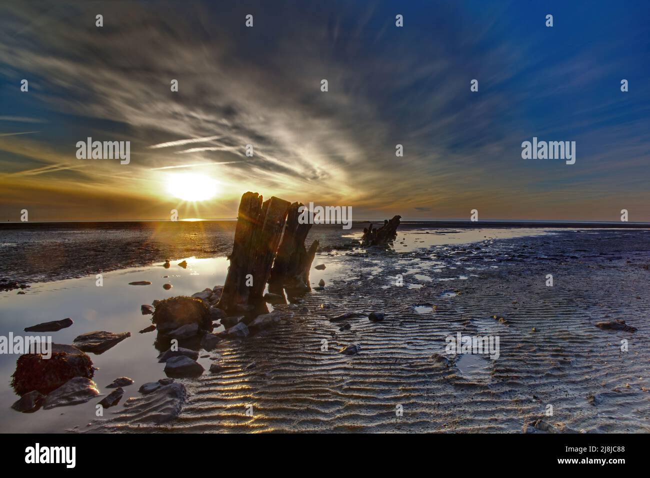 Sonnenuntergang über Holzgroyne in der Ebbe Stockfoto