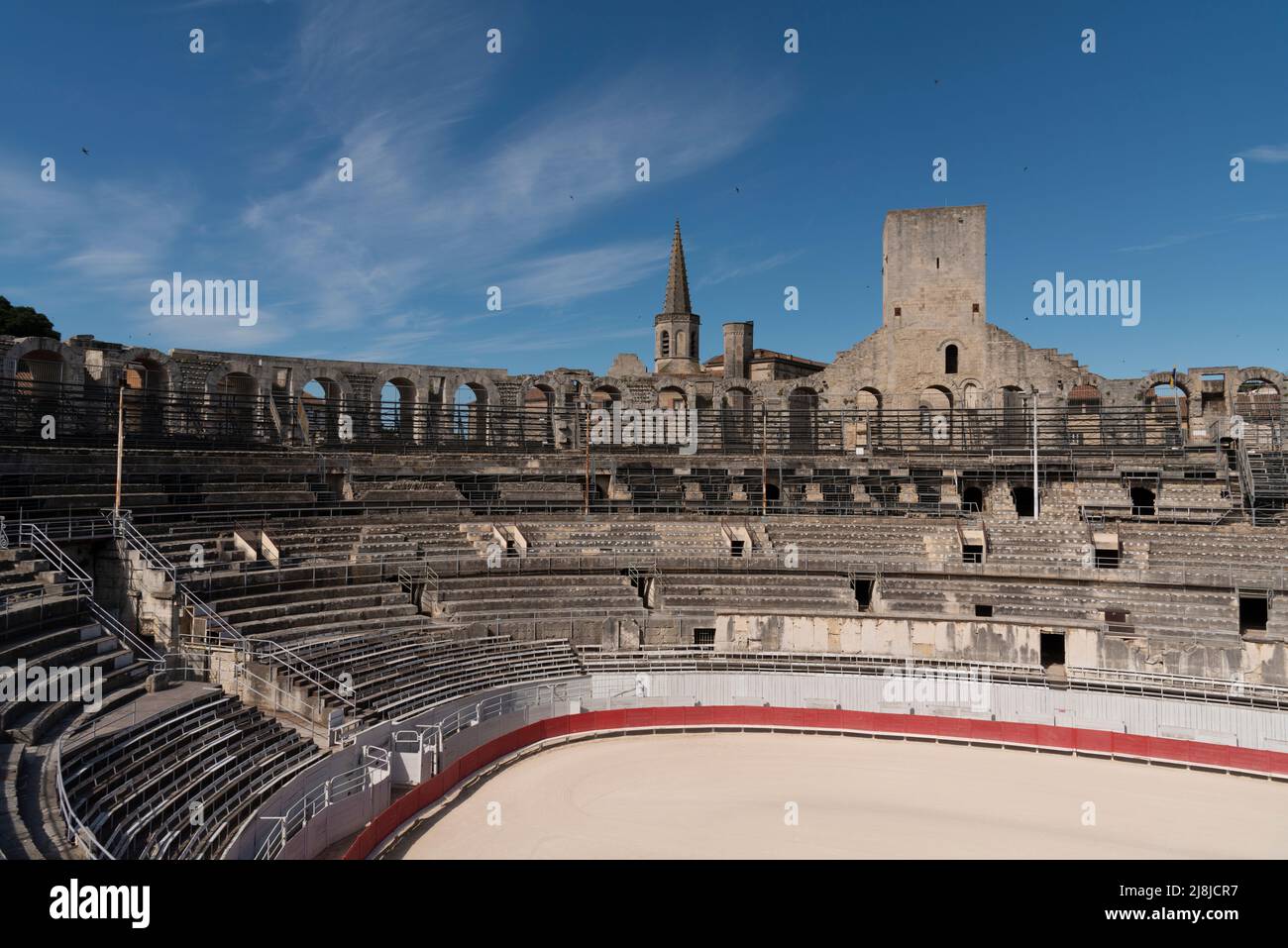 Arles Amphitheater (erbaut 90 n. Chr.). Die Türme auf der Spitze sind mittelalterliche Extras. Im Hintergrund der Glockenturm von Église Couvent des Cordeliers. Arles. Stockfoto