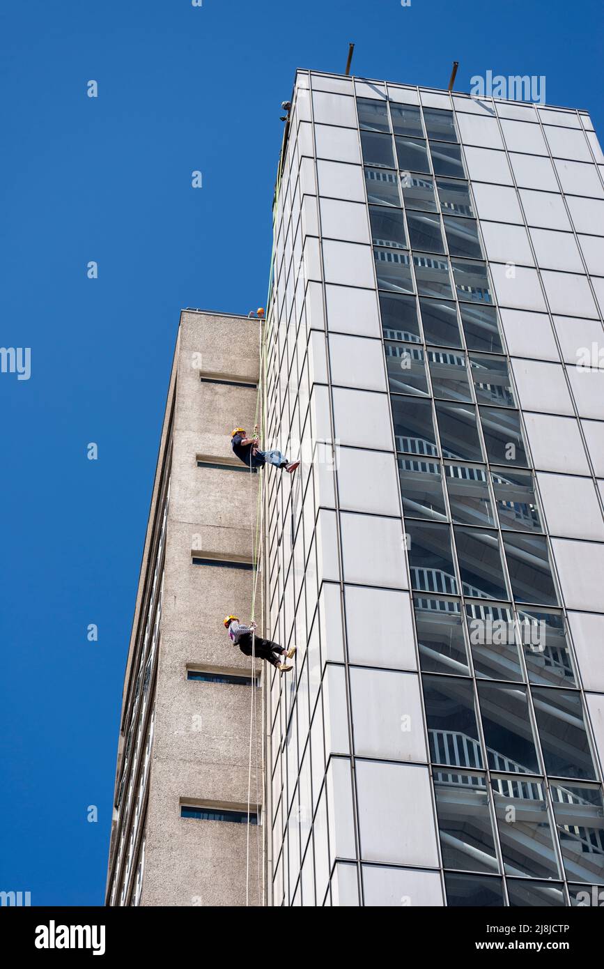 Zwei Personen, die sich aus wohltätigen Zwecken im hohen Hauptturm des Southend University Hospital abseilen. Hohes Abseilen. Treppen Stockfoto