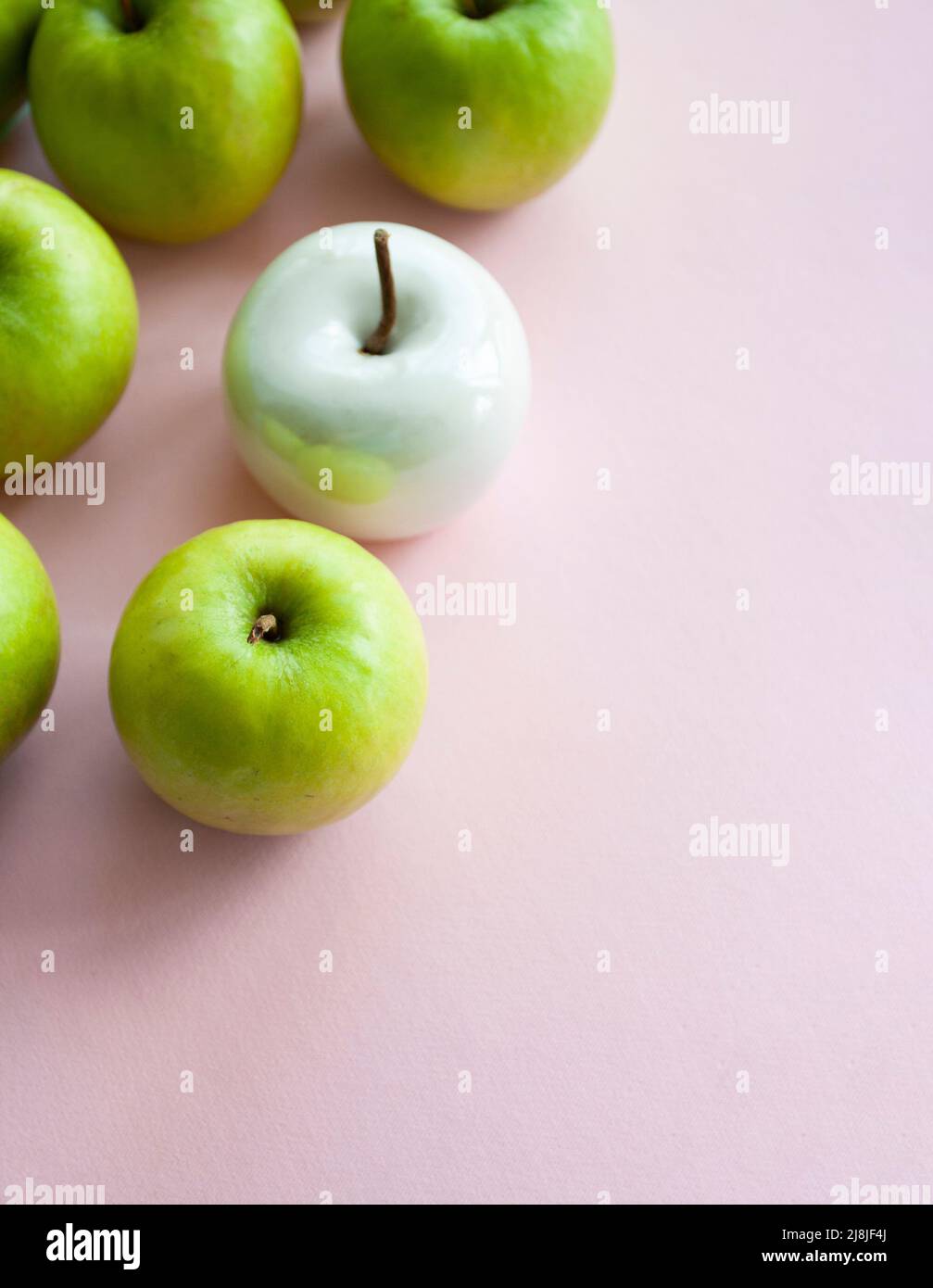 Viele leuchtend grüne Äpfel und eine weiße Keramik liegen auf einem rosa einheitlichen Hintergrund. Konzeptfoto. Stockfoto