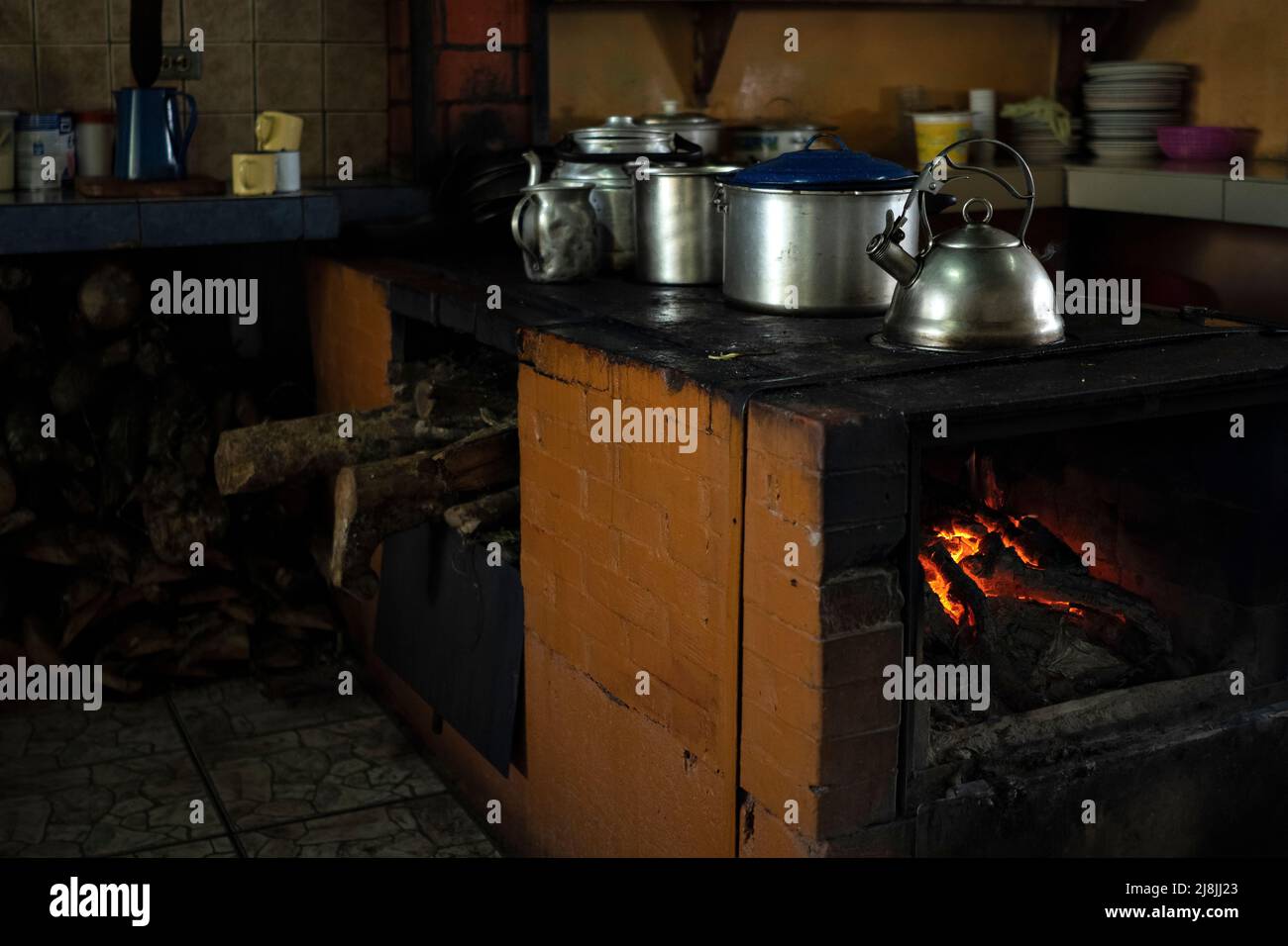 Traditionelle Küche mit Holzofen und Metalltöpfen. Unscharfer Hintergrund, Kopierbereich. Stockfoto