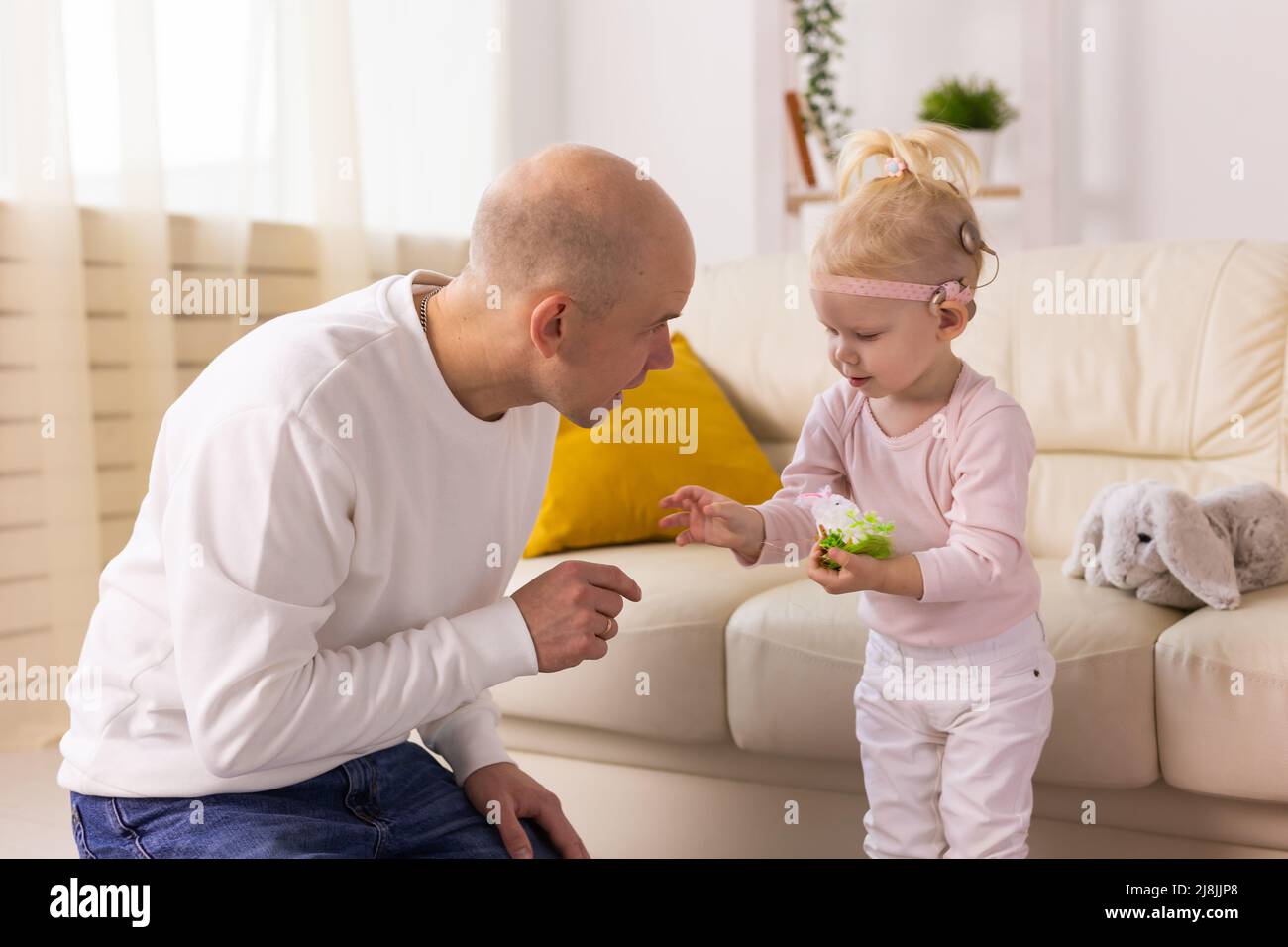Baby mit Cochlea-Implantaten spielt mit ihrer Mutter und ihrem Vater zu Hause. Stockfoto