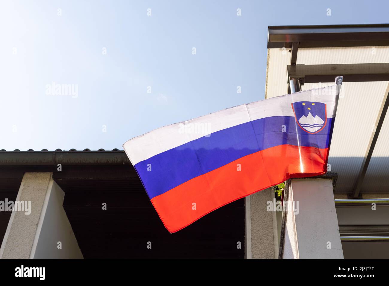 Die slowenische Nationalflagge winkt im Wind und die Sonne scheint Stockfoto