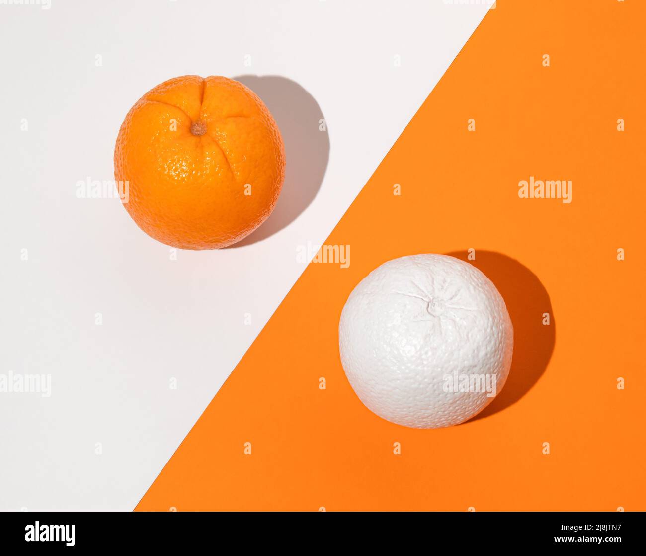 Kreatives Speiseangebot mit zwei Orangen. Weiß lackierte orange Früchte. Minimales Sommerkonzept. Flach liegend. Stockfoto