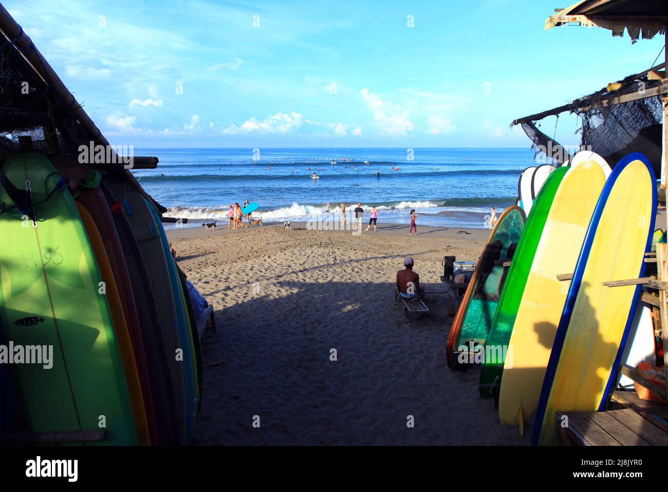 Blick auf Batu Bolong Beach in Canggu, Bali, Indonesien vom Parkplatz aus mit Verleih von Surfbrettern, Menschen, die am Strand entspannen und Surfer in den Wellen. Stockfoto