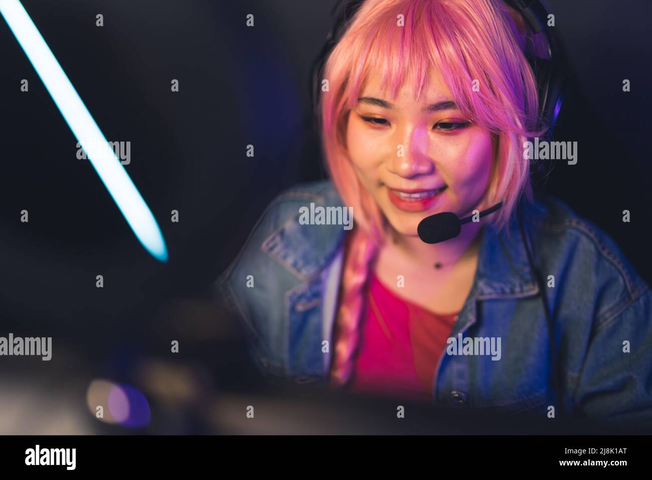 Mittlere Nahaufnahme von hübschen asiatischen weiblichen Spieler in Kopfhörern und rosa Perücke kopieren Raum Konzept . Hochwertige Fotos Stockfoto