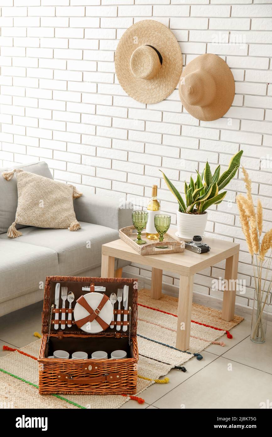 Korbkorb mit Geschirr für Picknick auf Teppich im Wohnzimmer Stockfoto