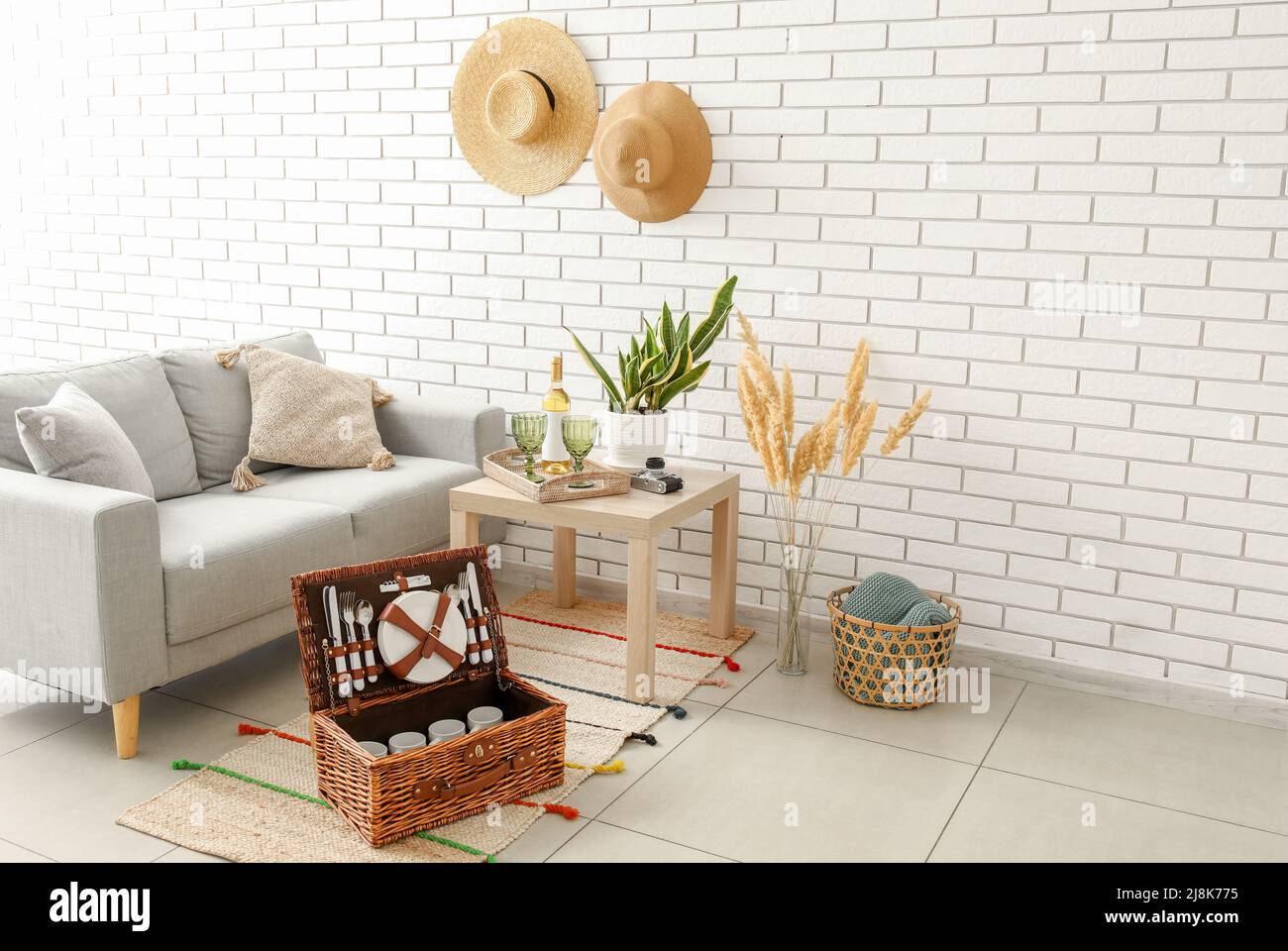 Korbkorb mit Geschirr für Picknick auf Teppich im Wohnzimmer Stockfoto