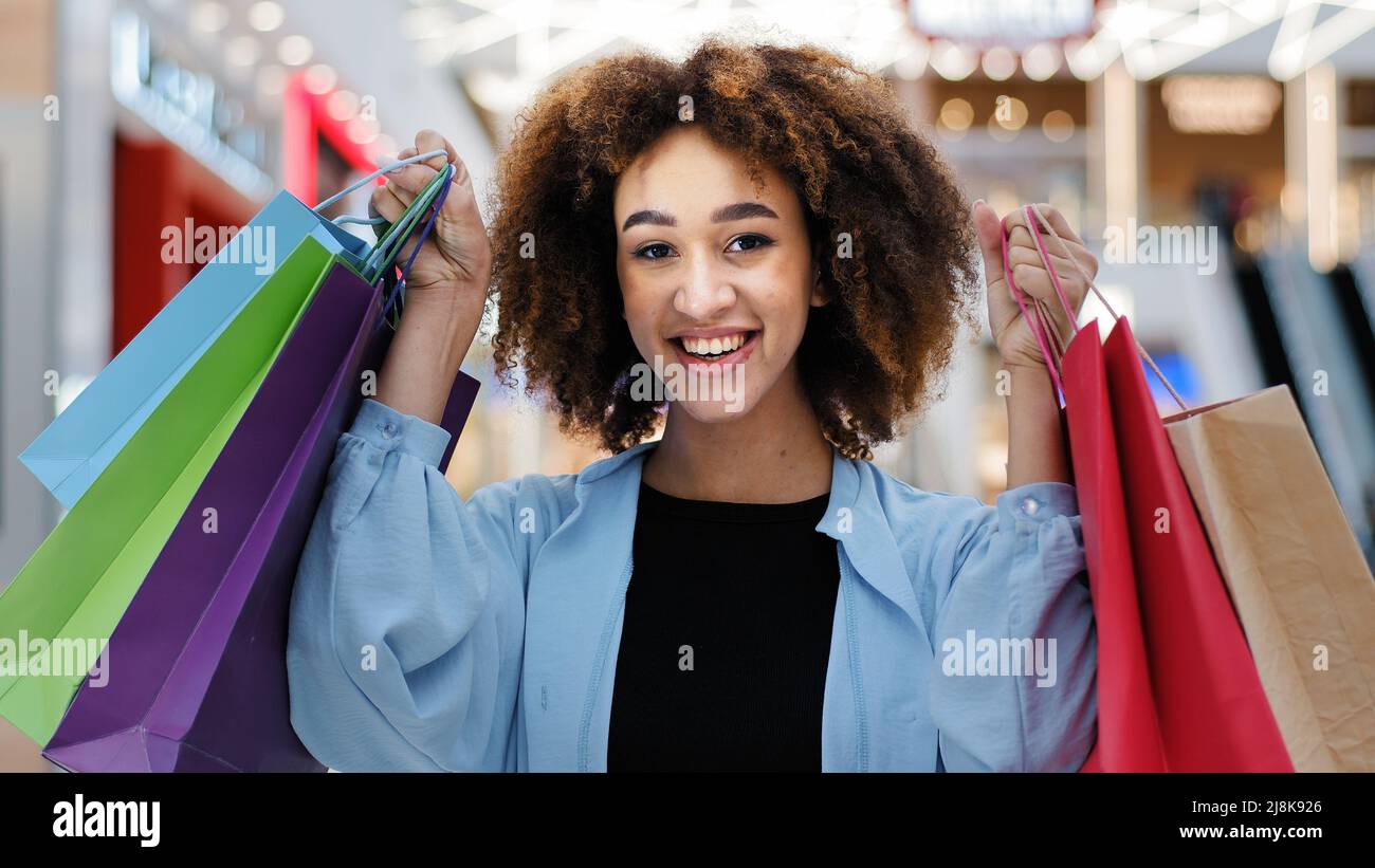 Nahaufnahme zufrieden glücklich afroamerikanische Frau Mädchen mit hellen Einkaufstaschen Einkäufe Pakete Genießen Sie Rabatte Blick auf Kamera lächelnd breit Stockfoto