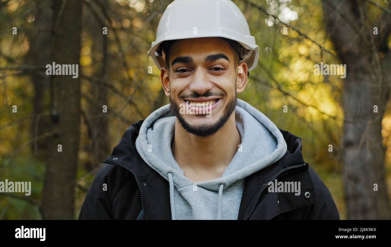 Männlich Porträt jung lächelnd hispanischen professionellen Arbeiter in Schutzhelm posiert im Freien Blick auf Kamera glücklich selbstbewussten Mann Forstingenieur Stockfoto