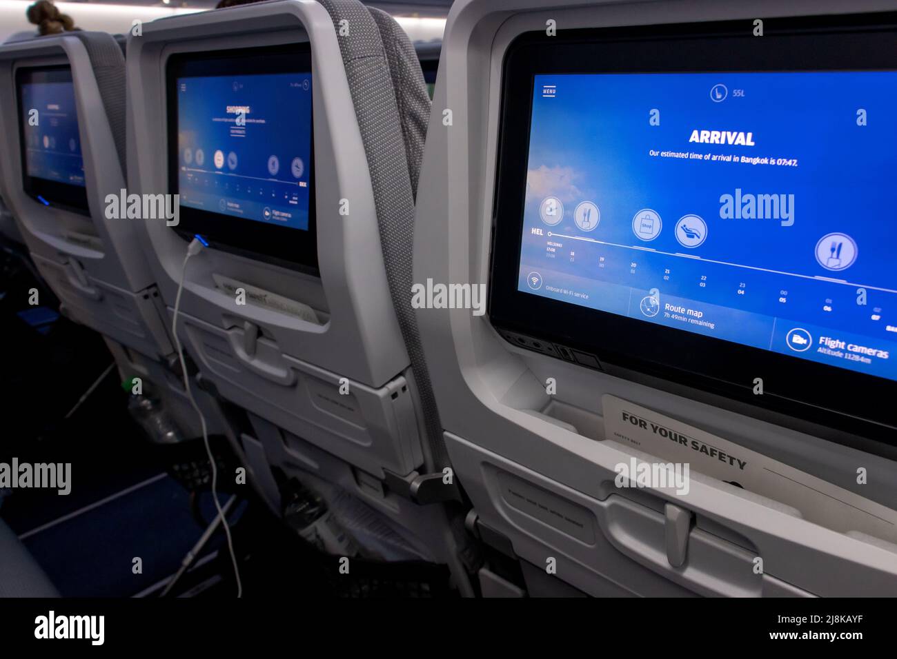 Eine Reihe von Monitoren auf dem hinteren Teil der Sitze in einem fliegenden Flugzeug Stockfoto