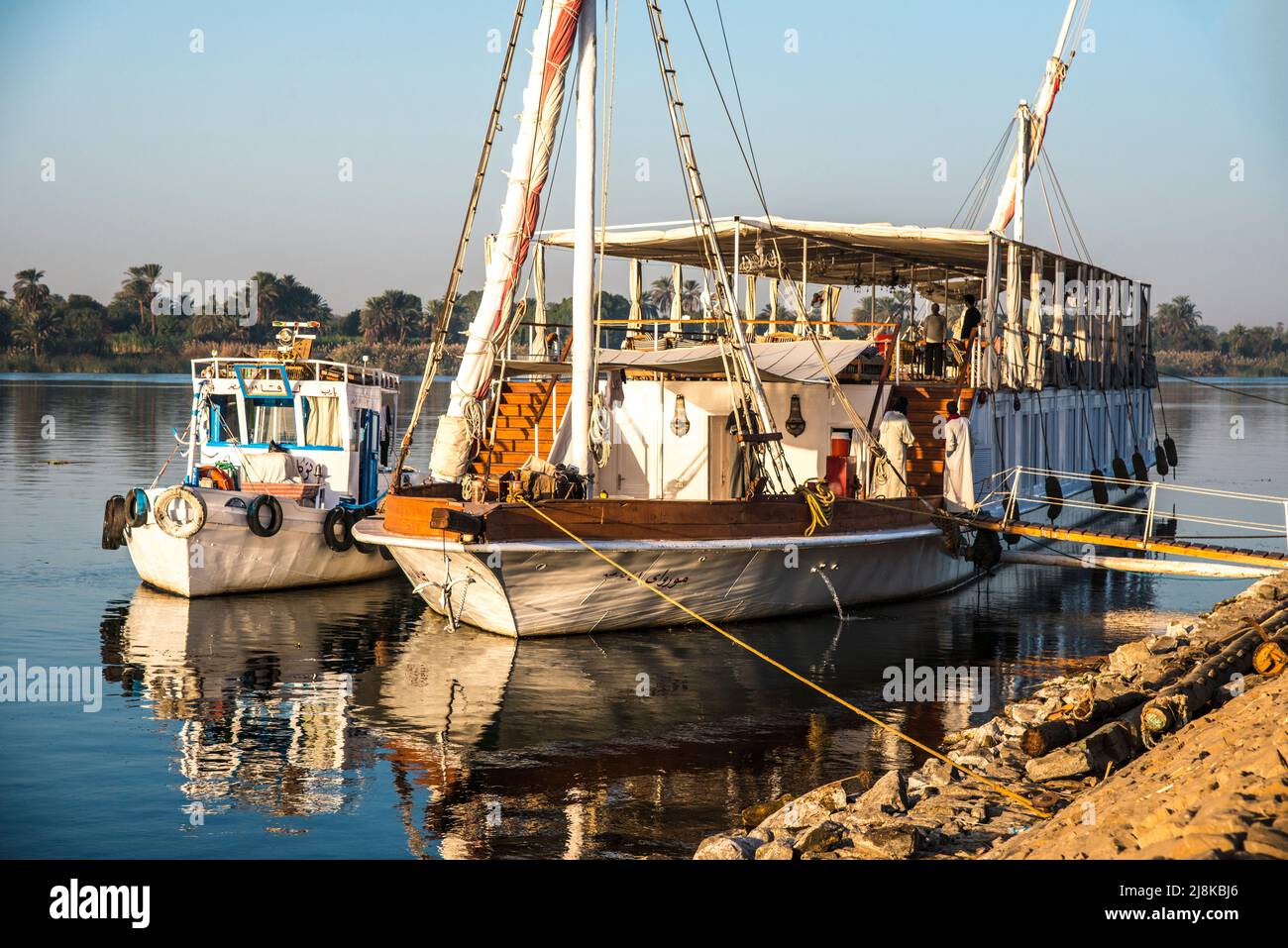 Schlepper und ein Nile Dahabiya Touristenboot sind an das Ufer des Nils gebunden Stockfoto