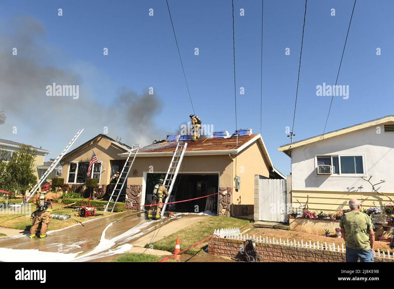Ein Hausbrand im Stadtteil Kearny Mesa von San Diego führte zu einem ersten Alarmeinsatz der Feuerwehr von San Diego. Das sich schnell bewegende Feuer zerstörte den Wohnteil des Hauses, wobei nur die Garage die Flammen überlebte. Nach einem vollständigen Dacheinsturz über den Wohnräumen mussten die Feuerwehrleute eine Luftleiter verwenden, um die Flammen zu löschen. Die beiden Bewohner des Hauses entkamen unverletzt. Die Ursache des Feuers wurde durch die jüngsten Arbeiten am Dach der Konstruktion bestimmt und der Gesamtschadens wurde auf $400.000 USD festgesetzt. Stockfoto