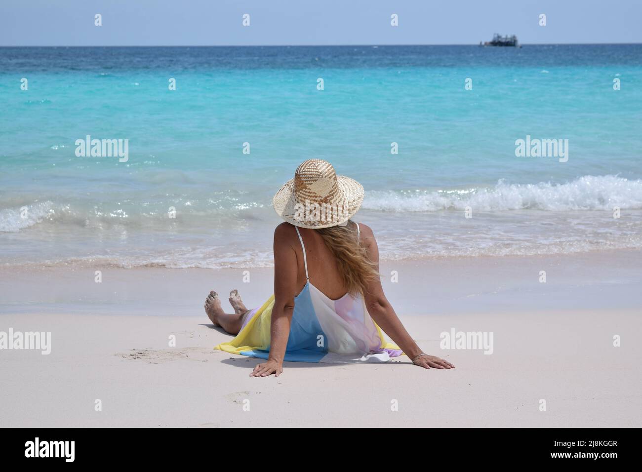 Wunderschöne gebräunte blonde Dame am weißen Sandstrand mit türkisfarbenem Wasser. Stockfoto