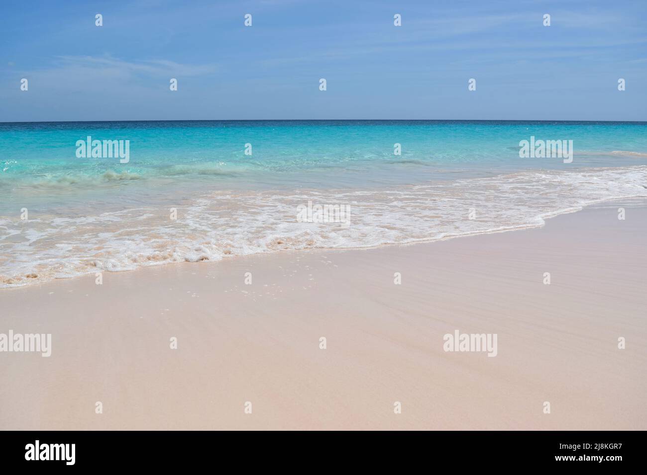 Ruhige Welle surft auf weißem Sand. Stockfoto