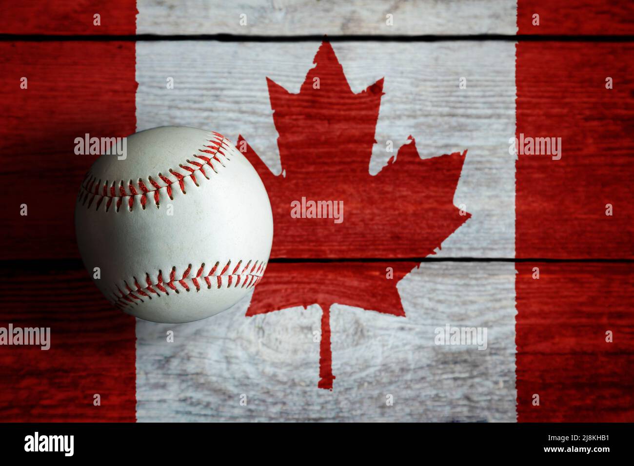 Leder-Baseballspiel auf rustikalem Holzhintergrund mit kanadischer Flagge mit Kopierraum bemalt. Kanada ist eine der führenden Baseballnationen der Welt. Stockfoto