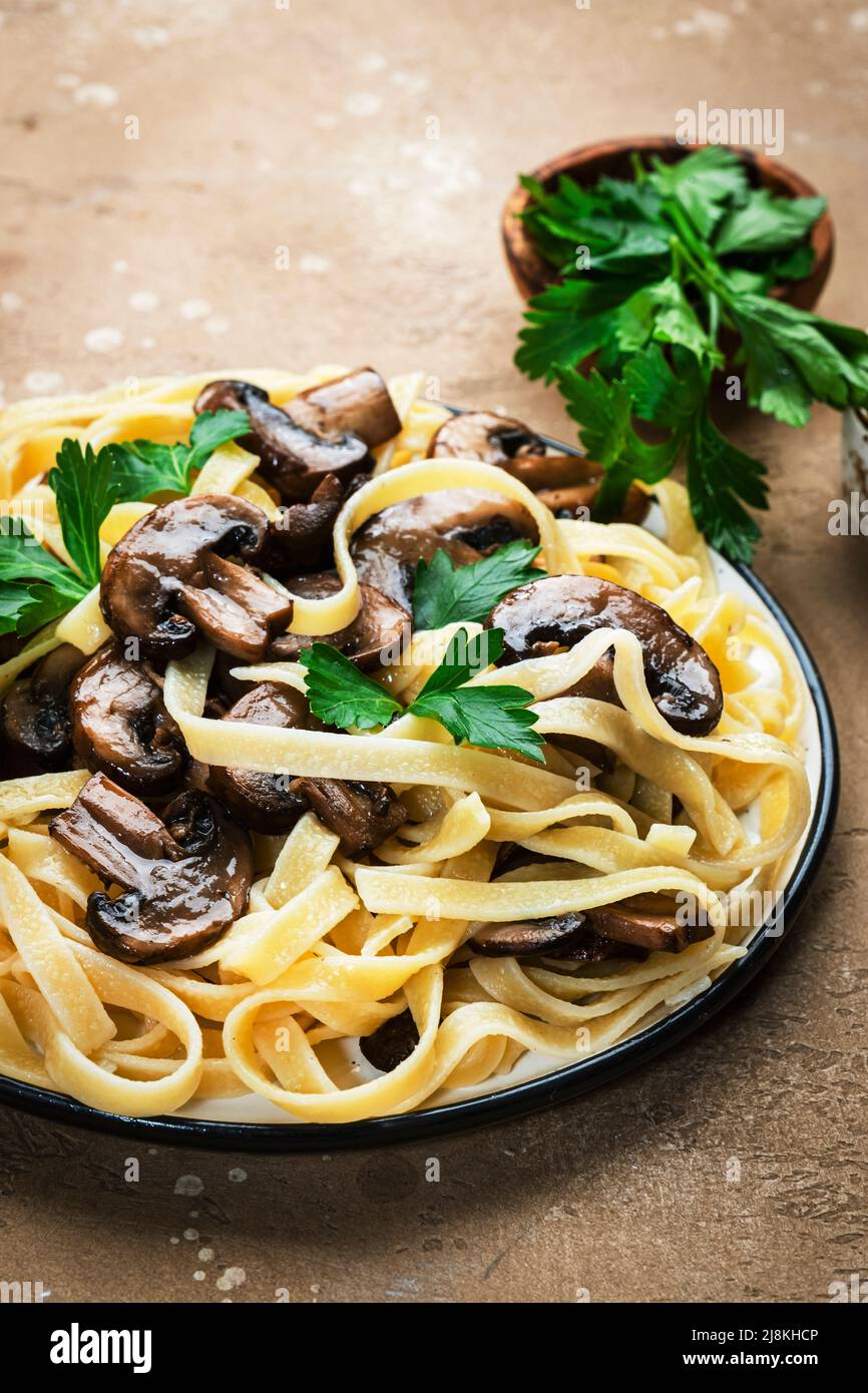 Gekochte Pasta mit Pilzen mit Petersilie auf dem Teller auf dem ...