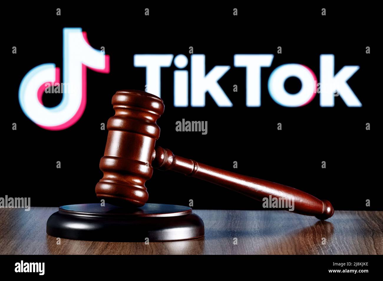 Gavel auf dem Tisch vor dem Hintergrund des TikTok Social-Networking-Service-Logos. Das Konzept des Trials. Stockfoto