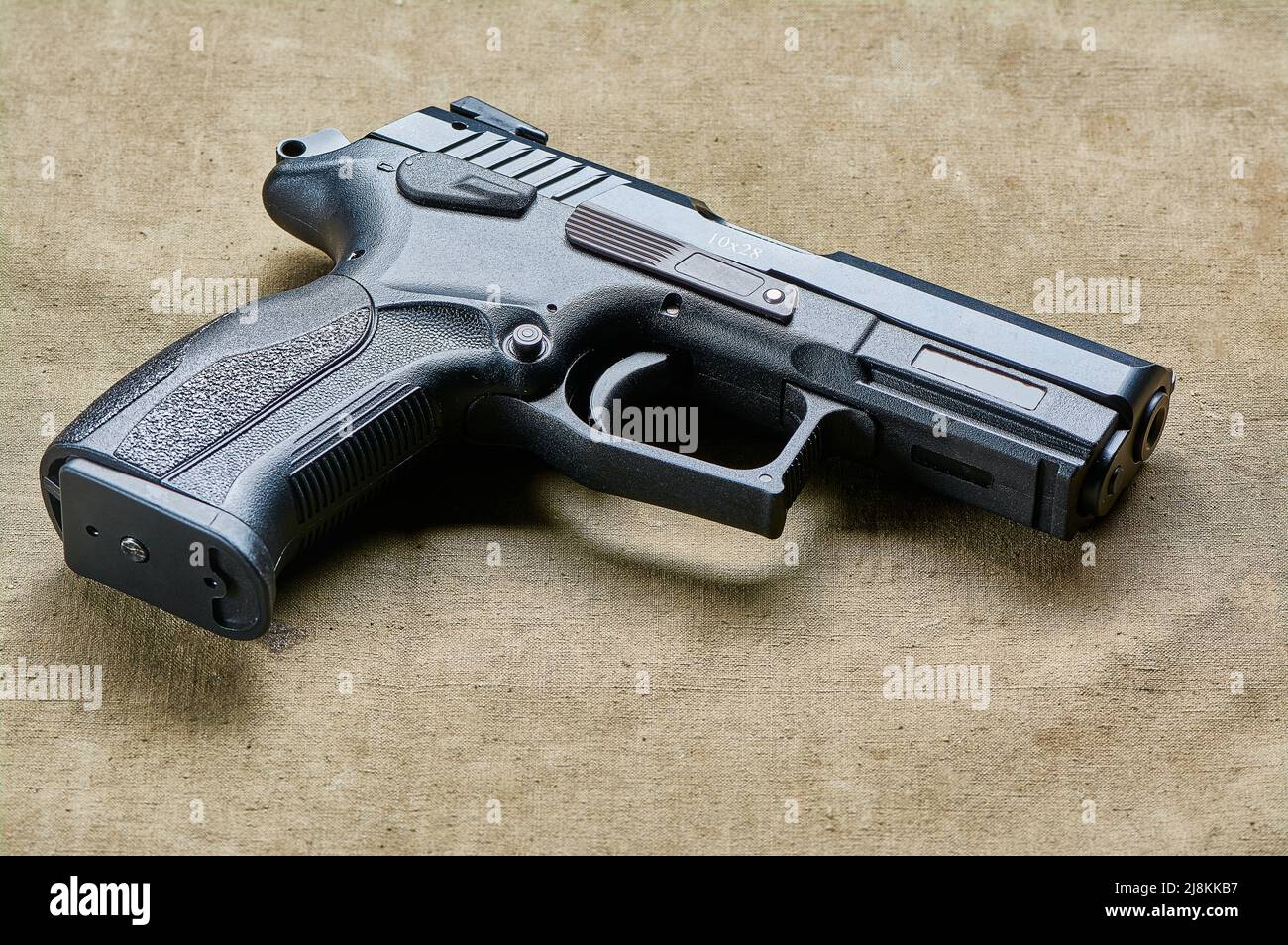 Eine schwarze Pistole in Nahaufnahme liegt auf einem Leinwandhintergrund, einer Feuerwaffe Stockfoto