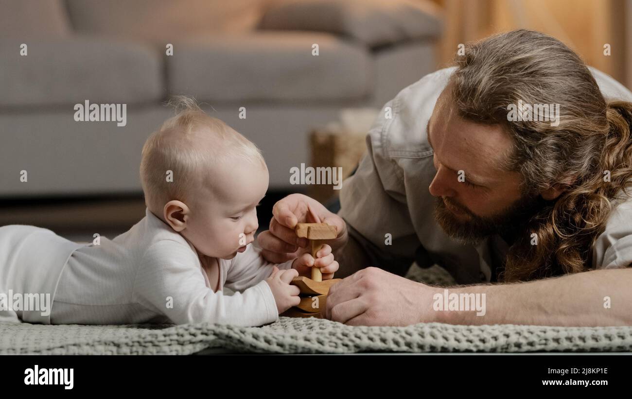 Kaukasische Familie bärtiger Vater Papa Papa mit kleiner Tochter Sohn Baby Baby neugeborenes Kleinkind spielt zu Hause auf dem Boden mit Spielzeug sammeln Holz Stockfoto