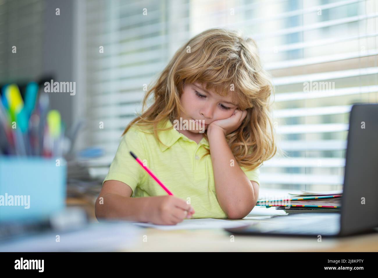 Müde Schuljunge während der Hausaufgaben. Kind schreibt Hausaufgaben in der Schulklasse. Lustige Kind Mädchen tun Hausaufgaben schreiben und lesen zu Hause. Wenig Stockfoto