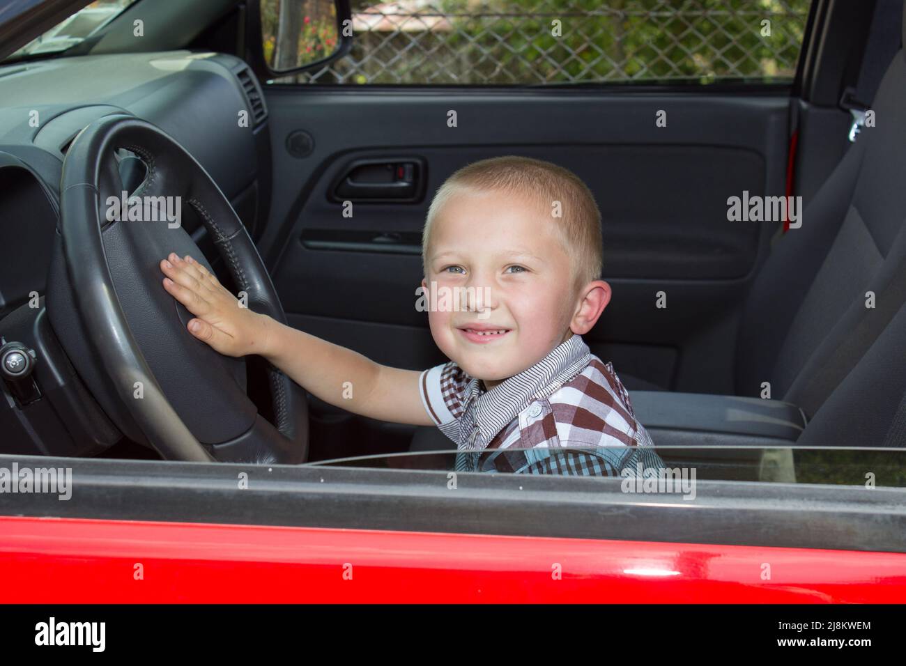 Kleiner Junge, der ein Auto fährt und glücklich sitzt Stockfoto