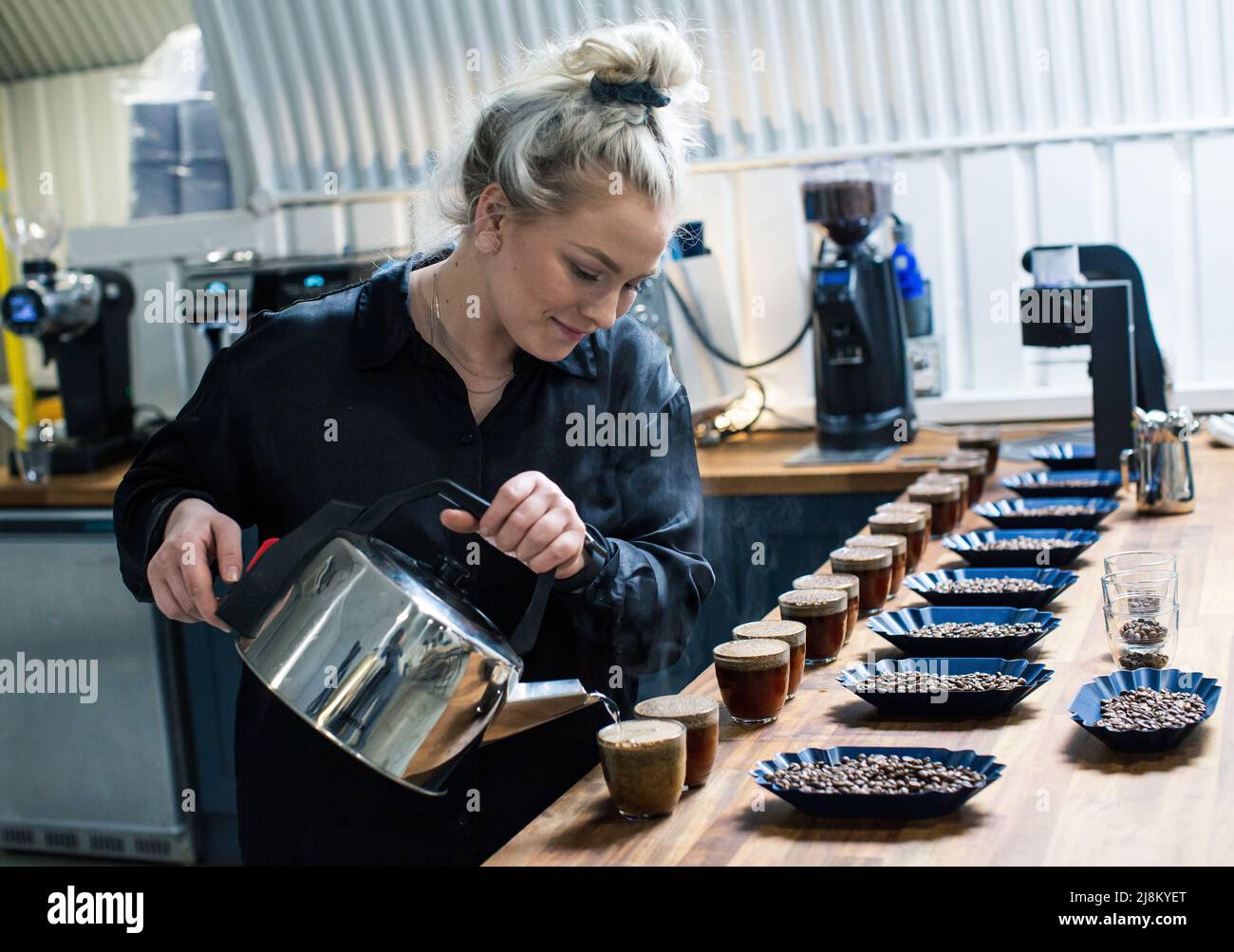 Frau gießt Wasser in Gläser für die Verkostung von Kaffee Schröpfen und Kaffee Verkostung Stockfoto