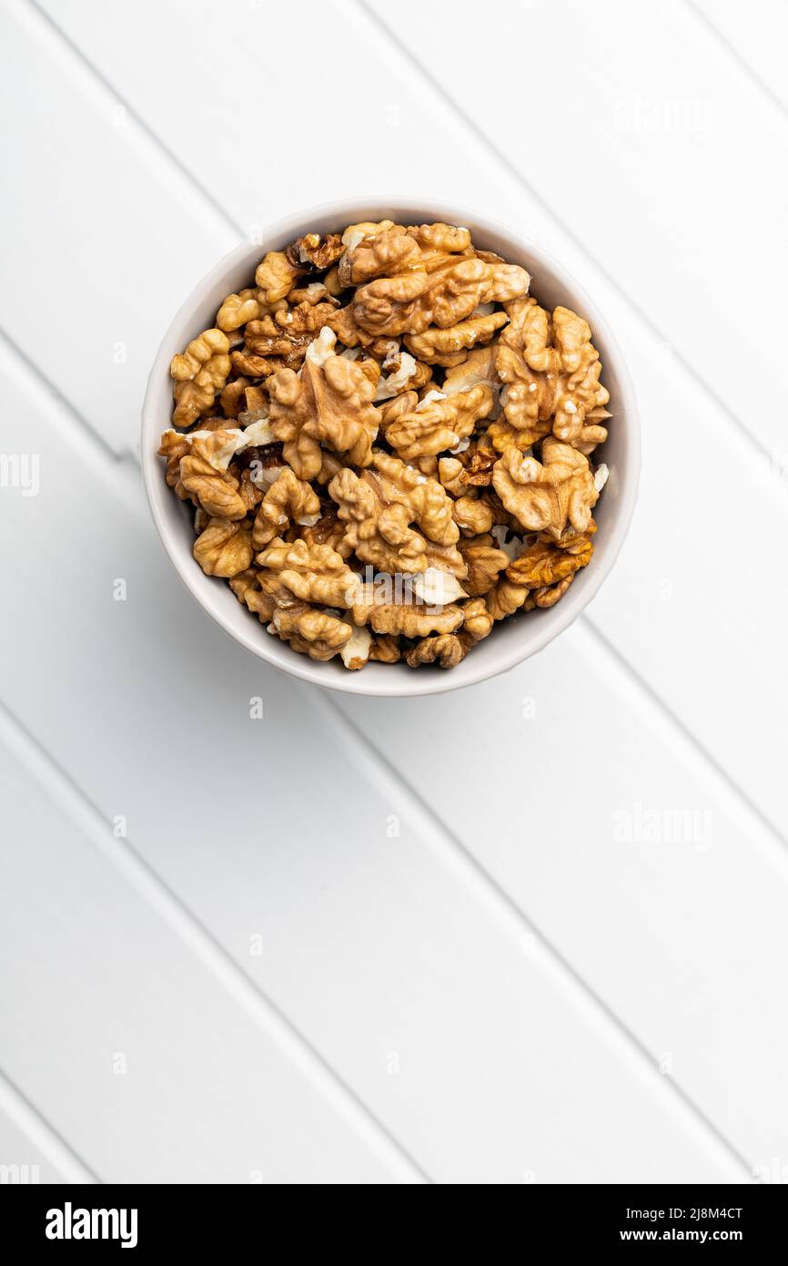 Geschälte Walnusskerne in einer Schüssel auf einem weißen Tisch. Draufsicht. Stockfoto