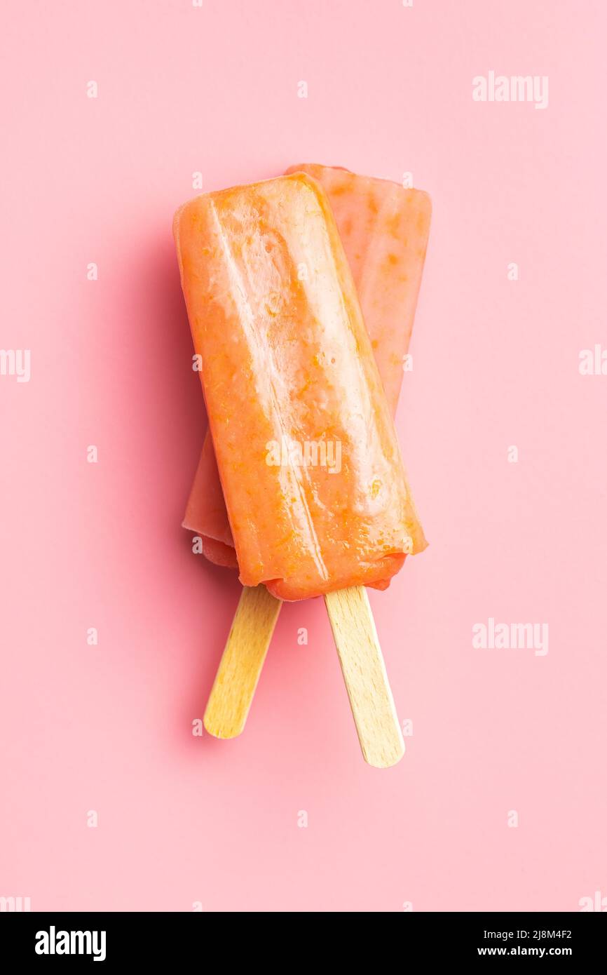Fruchtiges Eis lolly. Süßes Fruchteis auf einem rosafarbenen Tisch. Draufsicht. Stockfoto