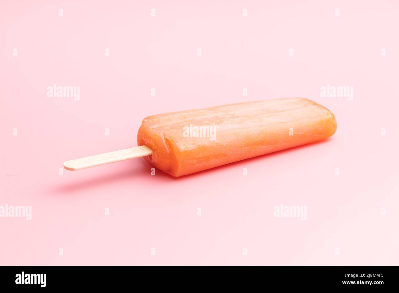 Fruchtiges Eis lolly. Süßes Fruchteis auf einem rosafarbenen Tisch. Stockfoto