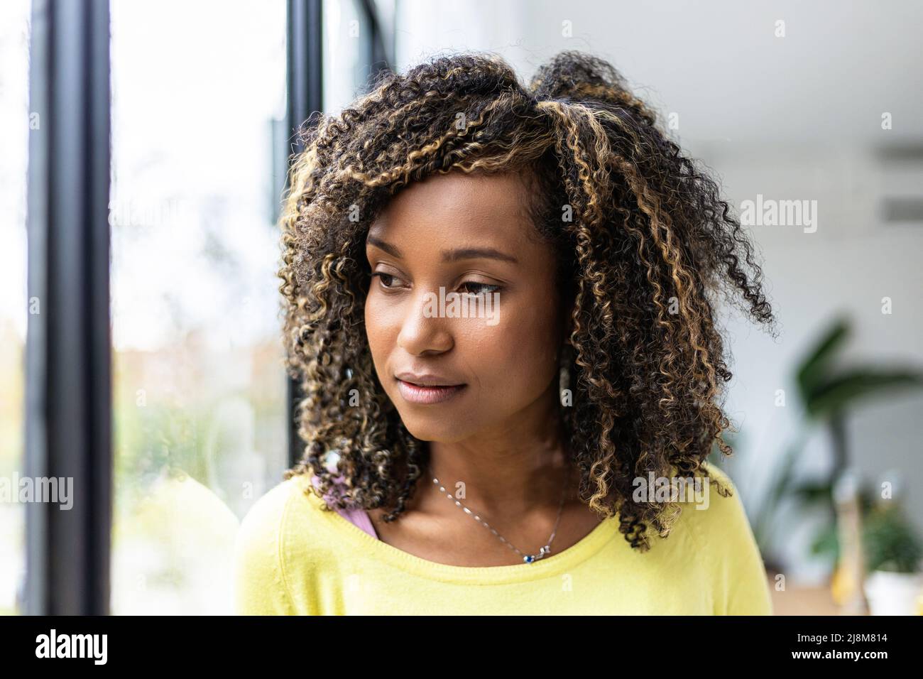 Porträt einer nachdenklichen jungen afrikanischen Frau, die aus dem Fenster schaut Stockfoto