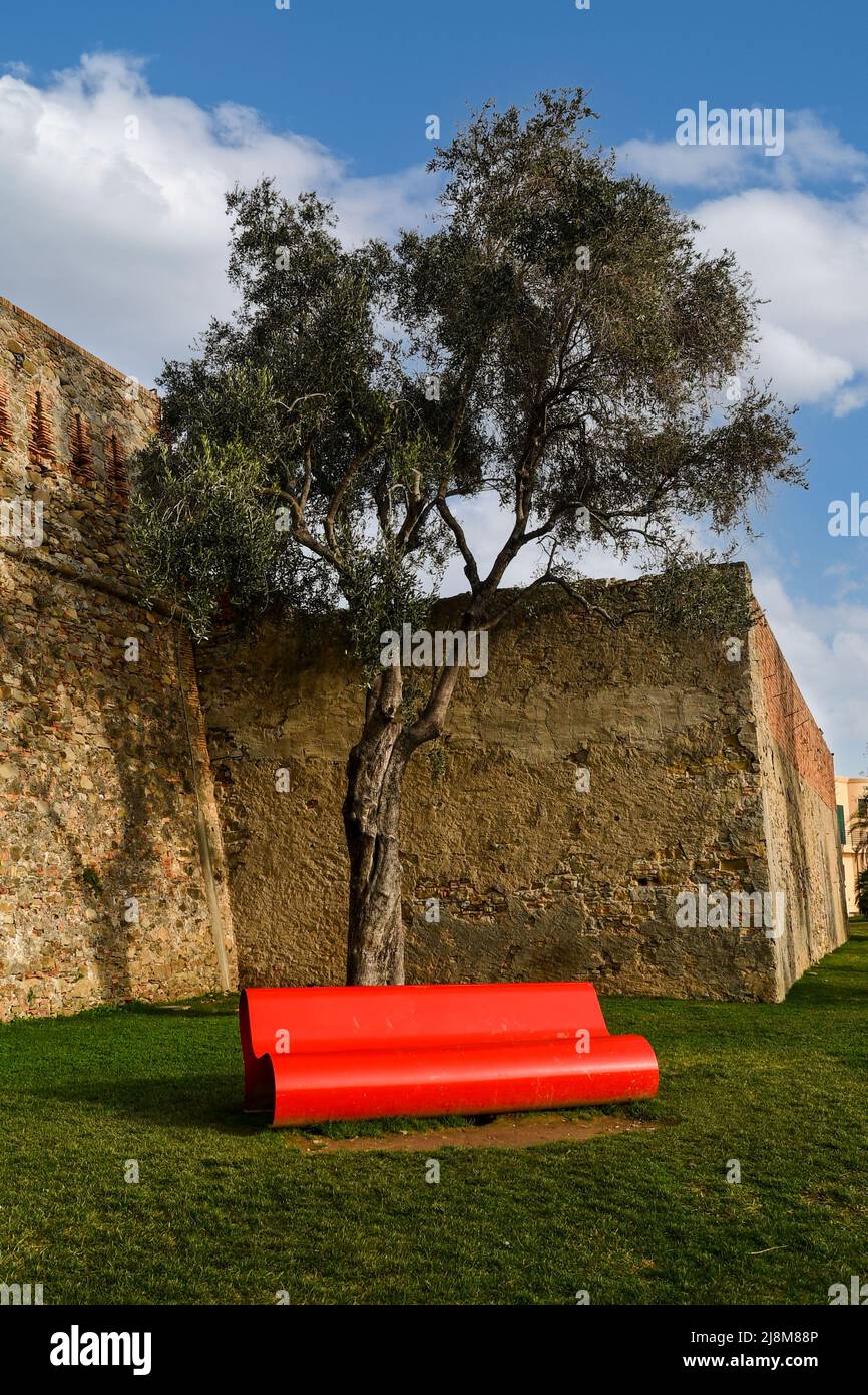 Detail der Außenseite des Forts von Santa Tecla (1756) mit einer modernen roten Bank unter einem Baum an einem sonnigen Tag, Sanremo, Imperia, Ligurien, Italien Stockfoto