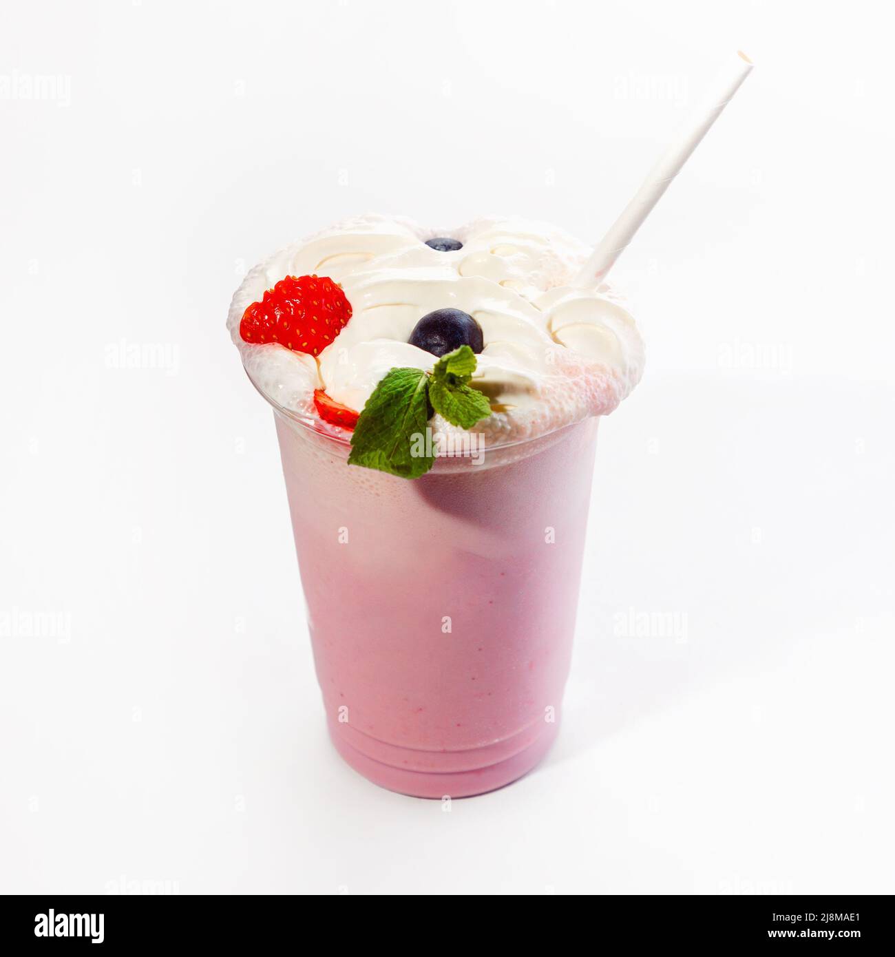 Kühler, köstlicher Milchshake mit Beerengeschmack und Schlagsahne, verziert mit Waldbeeren. Nahaufnahme auf weißem Hintergrund. Modell. Stockfoto