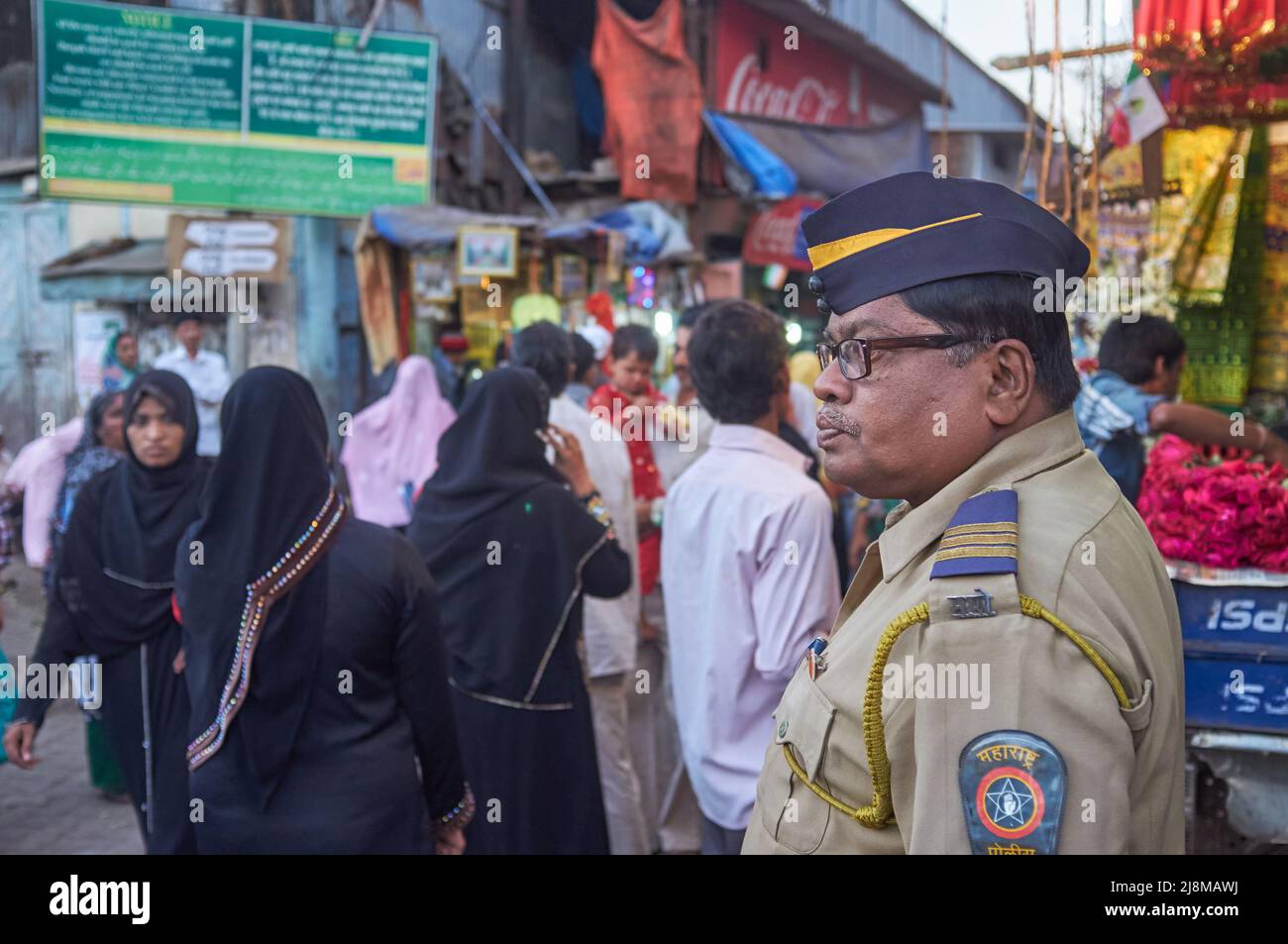 Ein Polizist wacht über die Menge, die Mira Datar Dargah in Darukhana, Byculla, Mumbai, Indien, besucht, einem muslimischen Schrein, in dem sich das Grab eines muslimischen heiligen befindet Stockfoto
