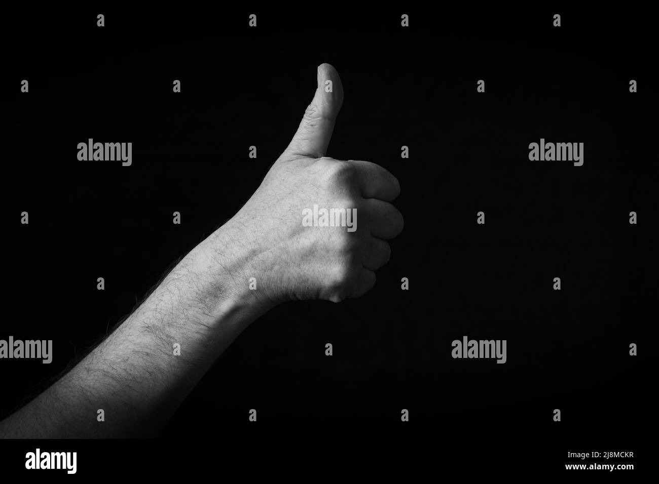 Dramatische Schwarz-Weiß-Bild von Thumbs up Emoji isoliert auf schwarzem Hintergrund Stockfoto