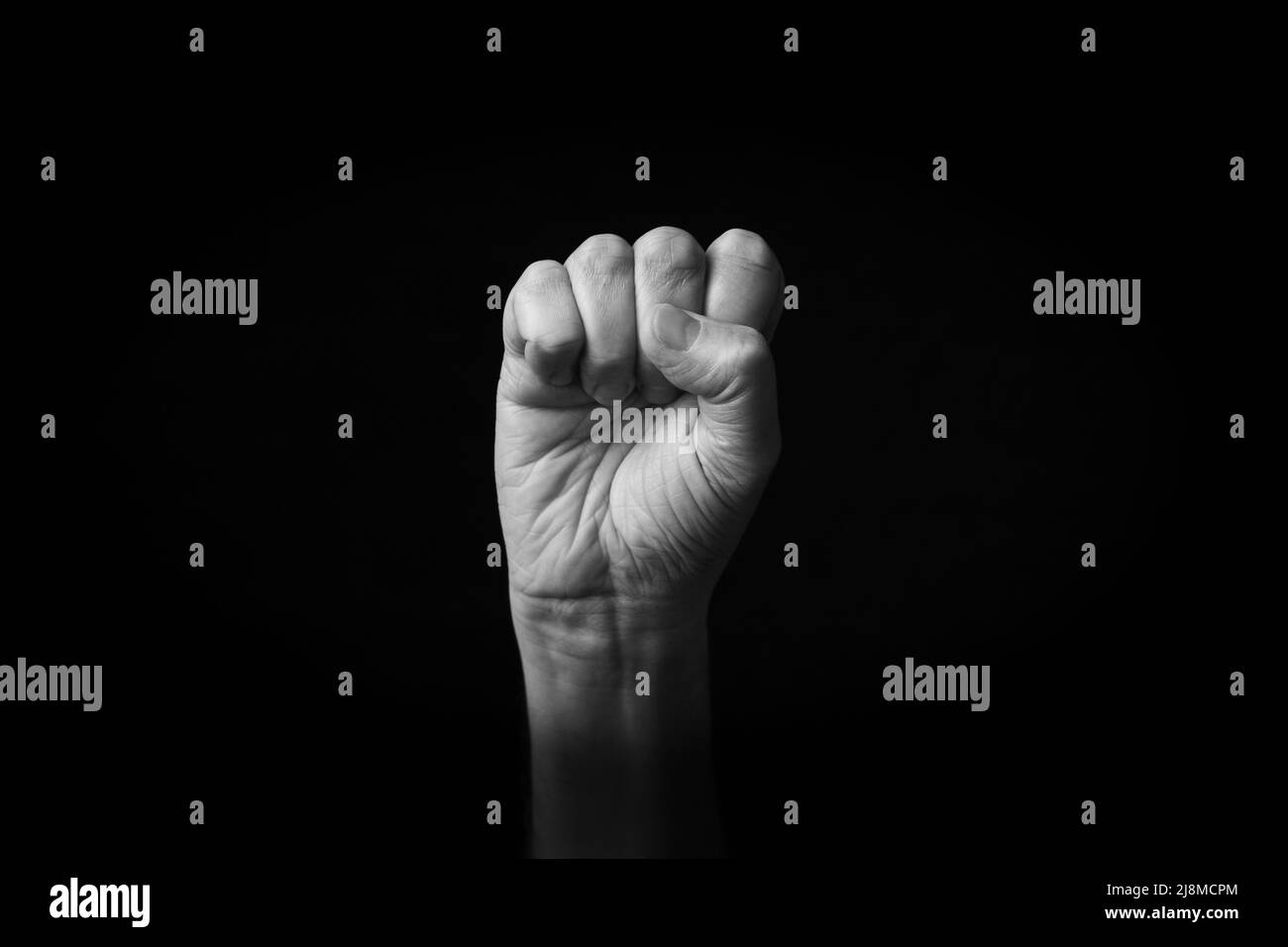 Dramatisches Schwarz-Weiß-Bild von Raised Fist Emoji isoliert auf schwarzem Hintergrund Stockfoto