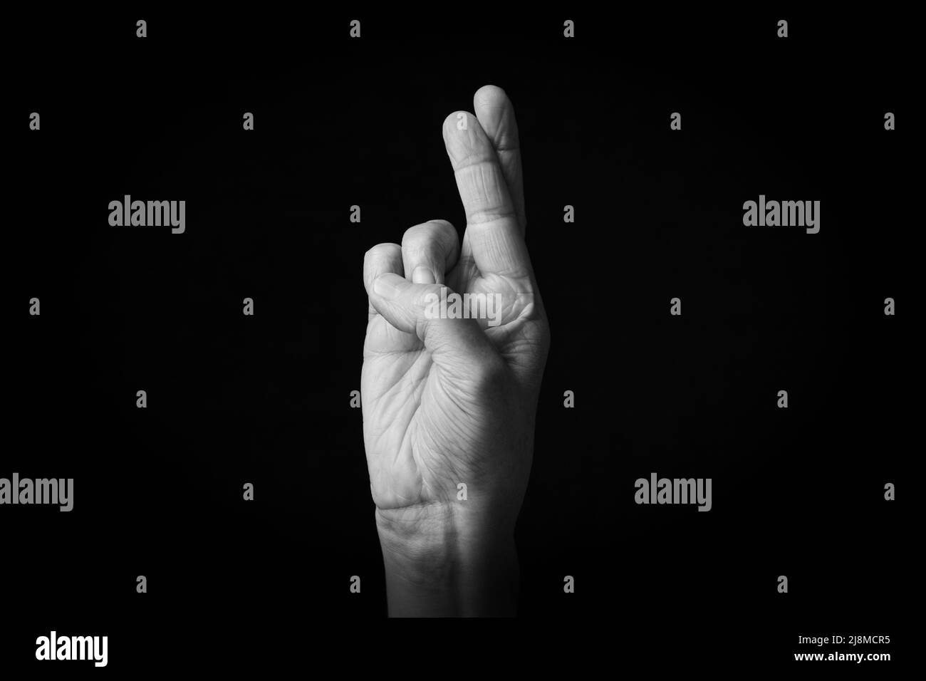 Dramatische Schwarz-Weiß-Bild von gekreuzten Fingern Emoji isoliert auf schwarzem Hintergrund Stockfoto