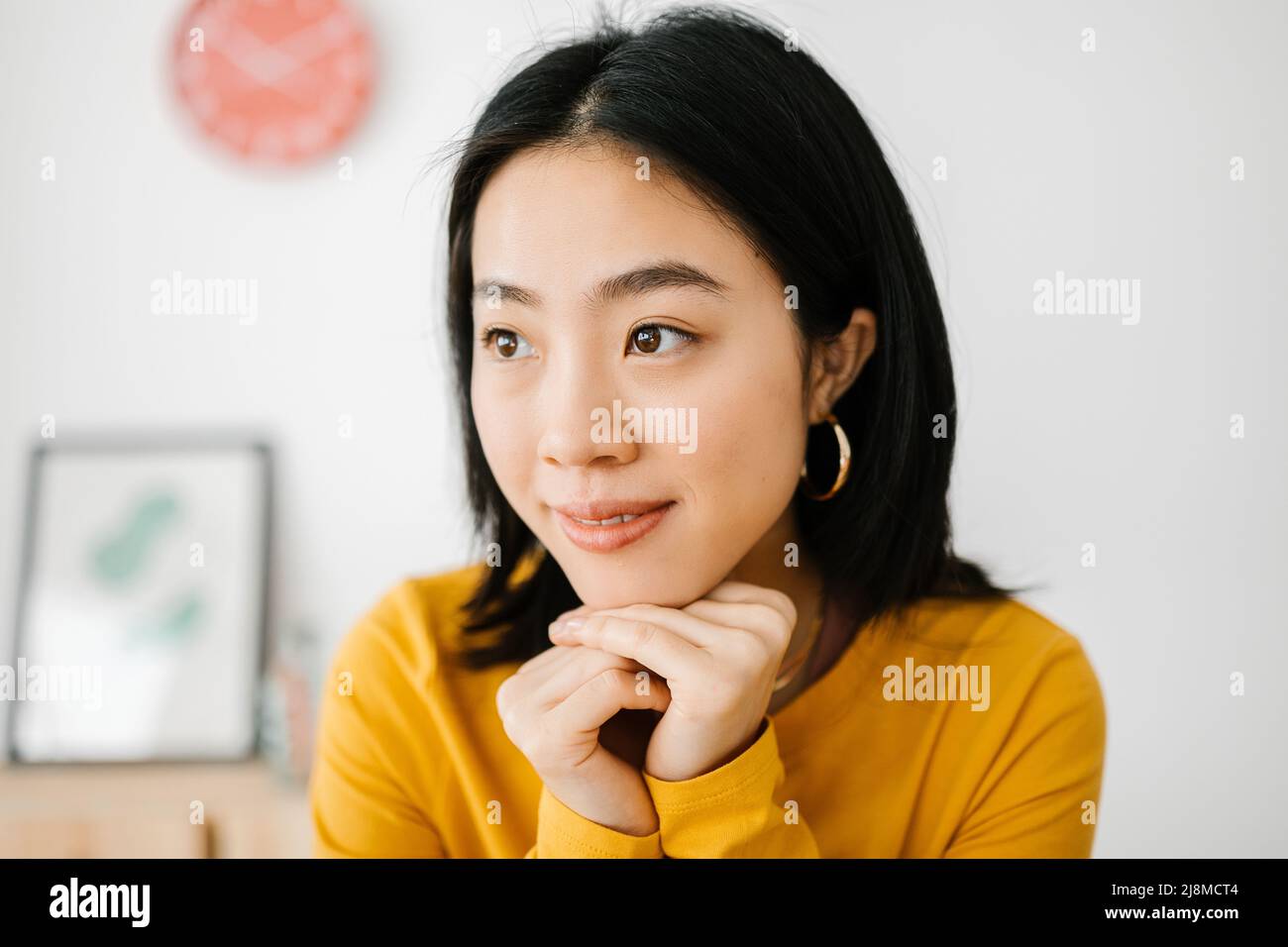 Nachdenkliche und nachdenkliche asiatische Frau schaut weg zu Hause bleiben Stockfoto
