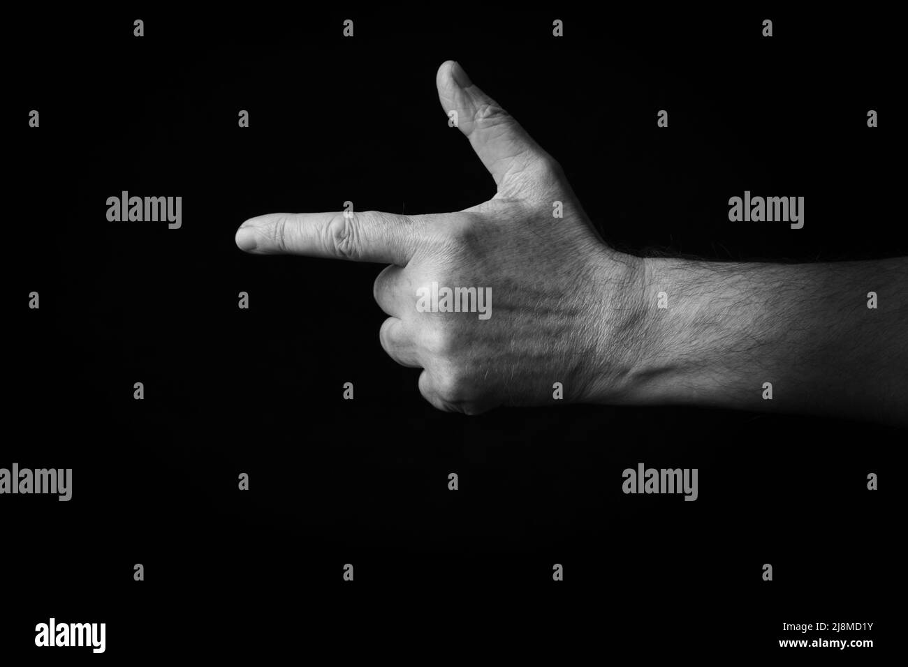 Dramatisches Schwarz-Weiß-Bild der Rückhand Index zeigt nach links Emoji isoliert auf schwarzem Hintergrund Stockfoto