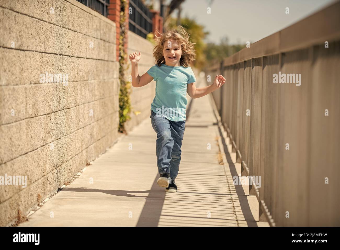 Kindheitsspiel. Fröhlicher Junge hat Spaß beim Laufen auf der Promenade. Spiele im Freien. Aktivurlaub im Sommer Stockfoto